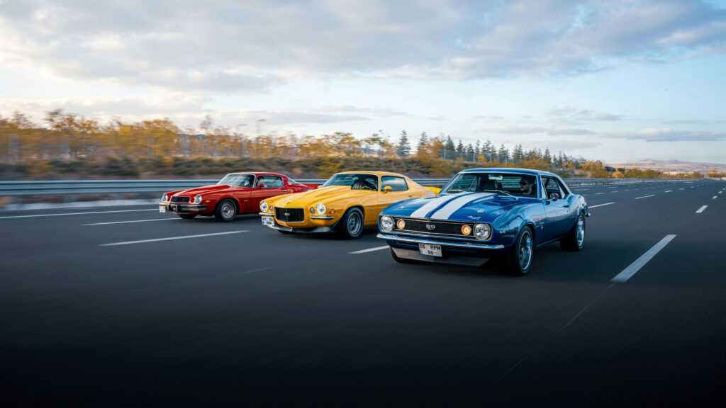 Three colorful classic muscle cars driving on a highway in Ankara, Türkiye.