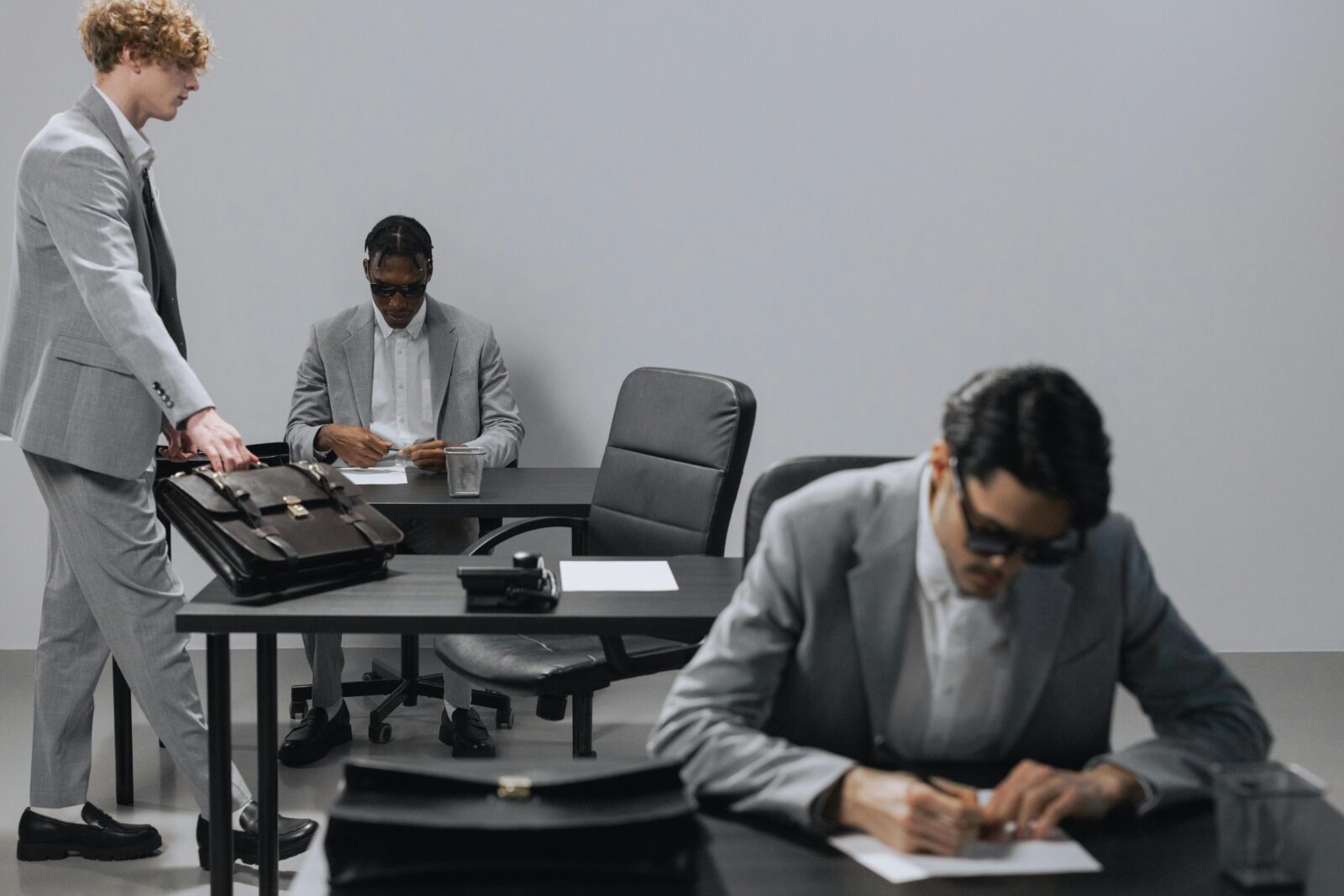 Business office with diverse employees in gray suits working at desks in an indoor setting.